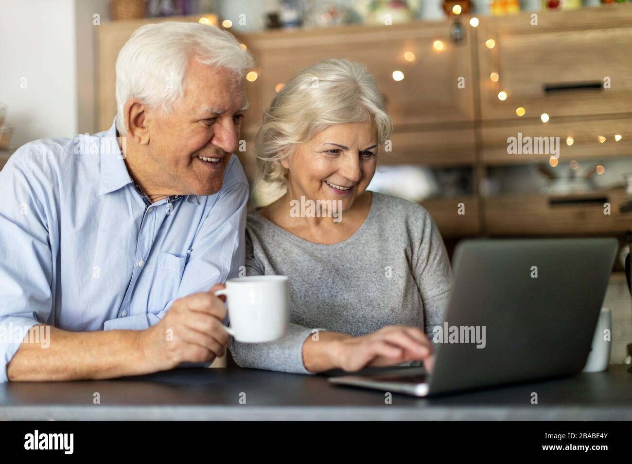 Senior couple using laptop in their kitchen Stock Photo