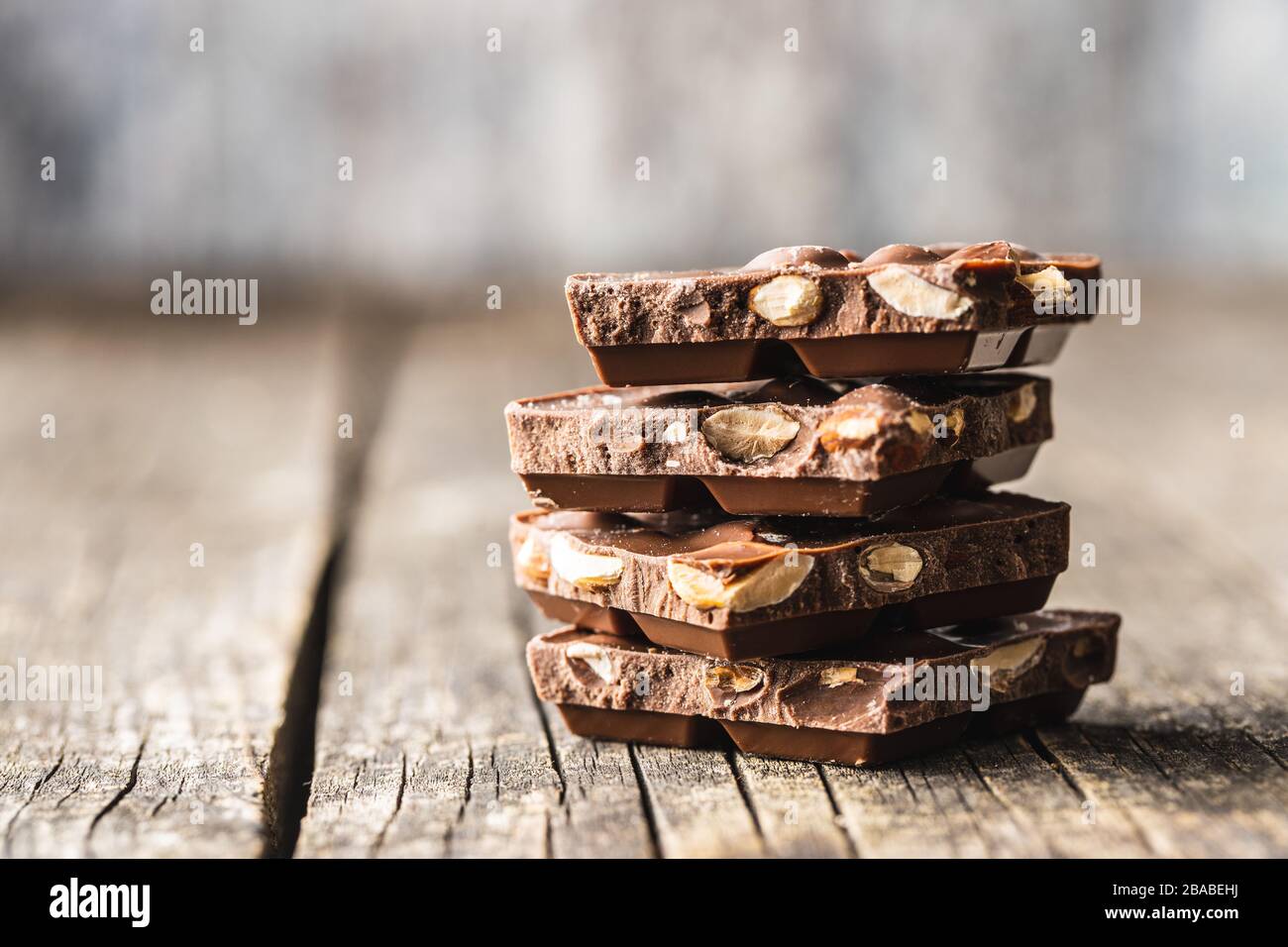 Dark nut chocolate. Broken chocolate bar on black kitchen table. Pile