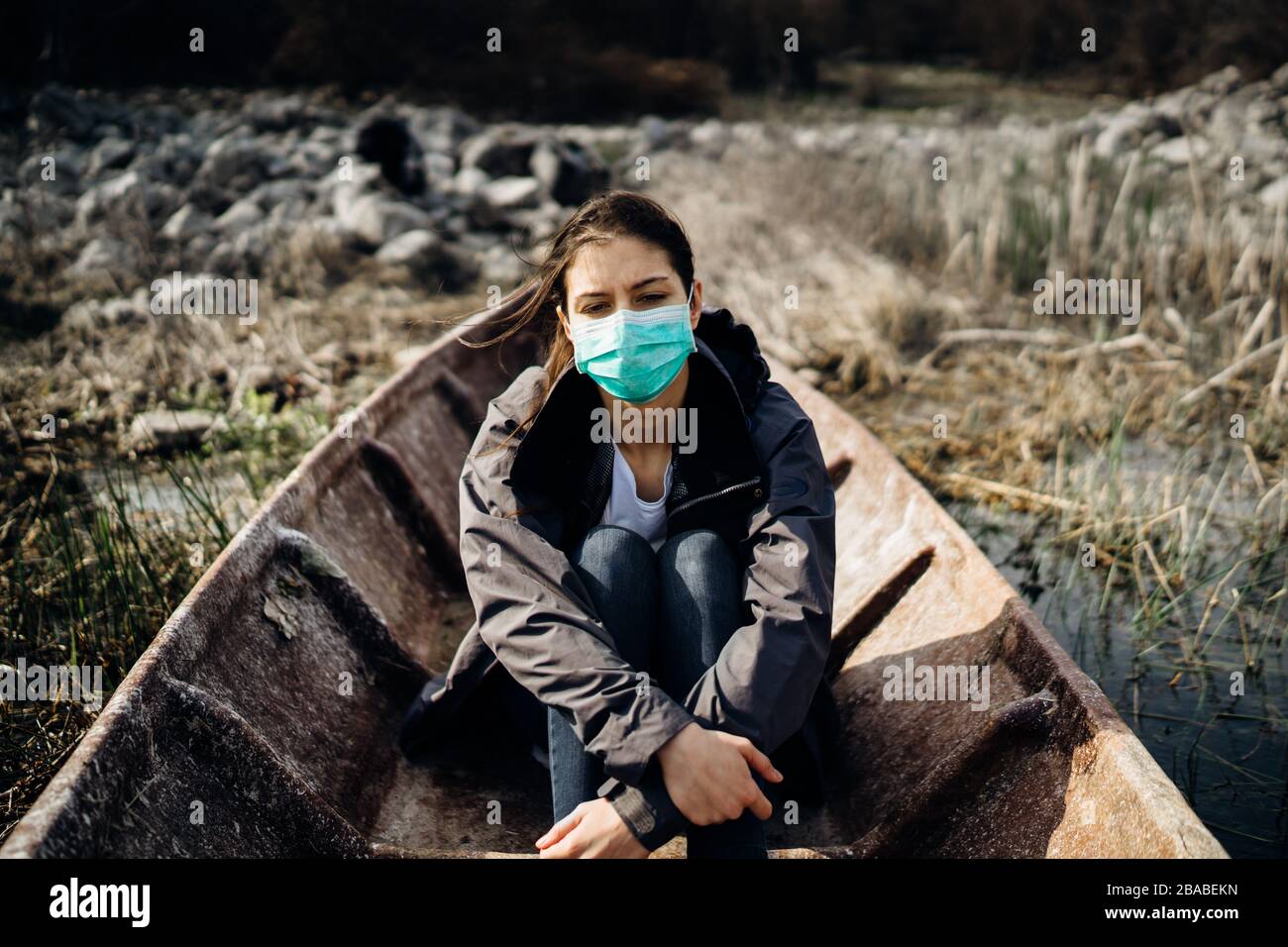 Woman with mask in despair and fear of coronavirus.Mental escape.Emotional worried person in boat.Imigrant.Apocalipse salvation.Pandemic depression Stock Photo
