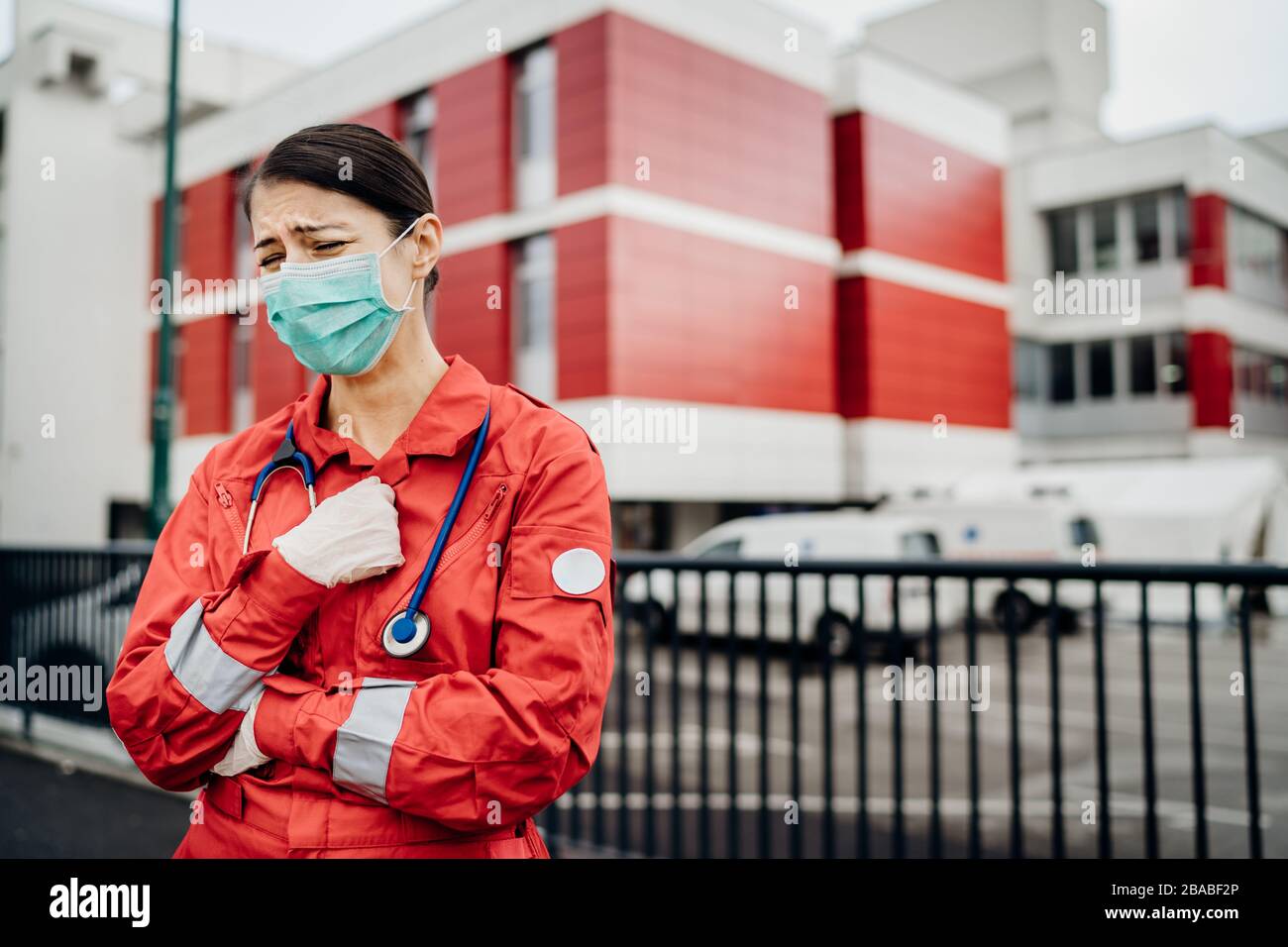 Crying paramedic in front of isolation hospital facility.Mental melt down of medical professional.Emergency room doctor in fear and stress,pressure Stock Photo