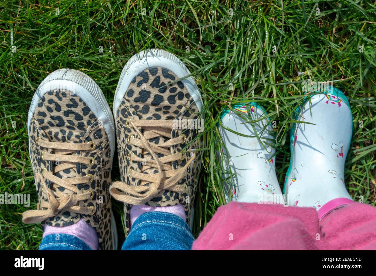a close view of two pairs of feet a little girl and her mom with animal print and flowers on Stock Photo