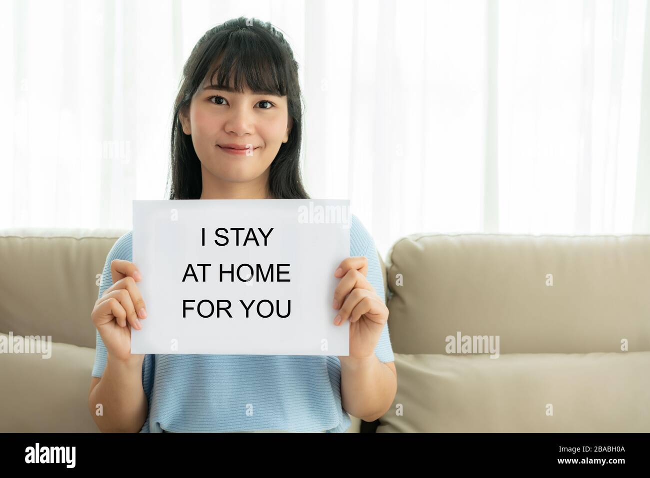 Asian woman holding sheet of paper with text I stay at home for you to cheer medical staff to protect virus and take care of their health from COVID-1 Stock Photo
