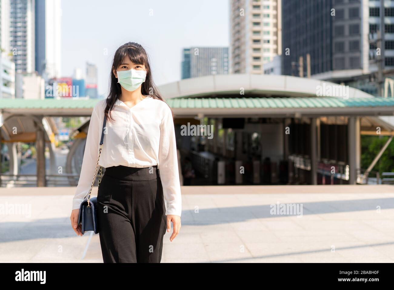 Young stress Asian businesswoman in white shirt going to work in pollution city she wears protection mask prevent PM2.5 dust, smog, air pollution and Stock Photo