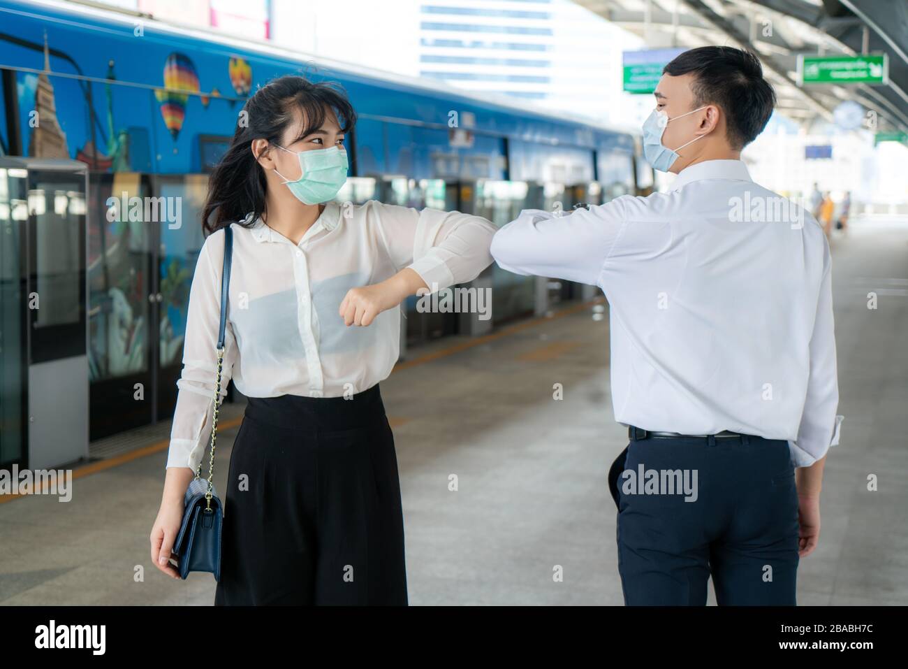 Elbow bump is new novel greeting to avoid the spread of coronavirus. Two Asian business friends meet in subway station. Instead of greeting with a hug Stock Photo