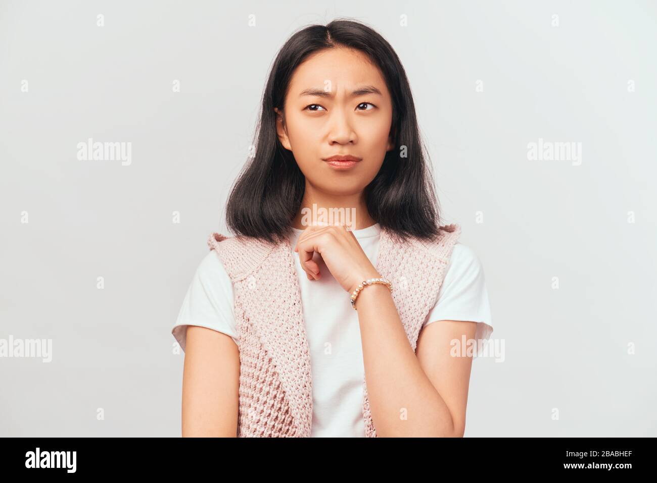 Girl frowns in disbelief, looks away, pursing lips Stock Photo