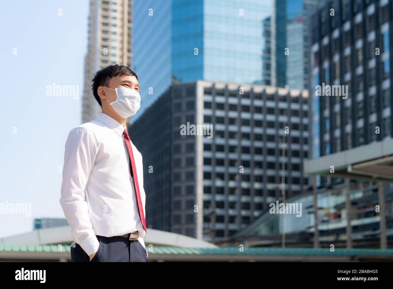 Young smart Asian businessman in white shirt going to work in pollution city he wears protection mask prevent PM2.5 dust, smog, air pollution and COVI Stock Photo