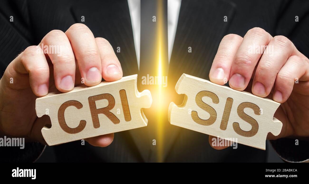 Man breaks two puzzles with word Crisis. Avoid or end economic political crisis. Recovery, overcoming consequences. New business and industry opportun Stock Photo