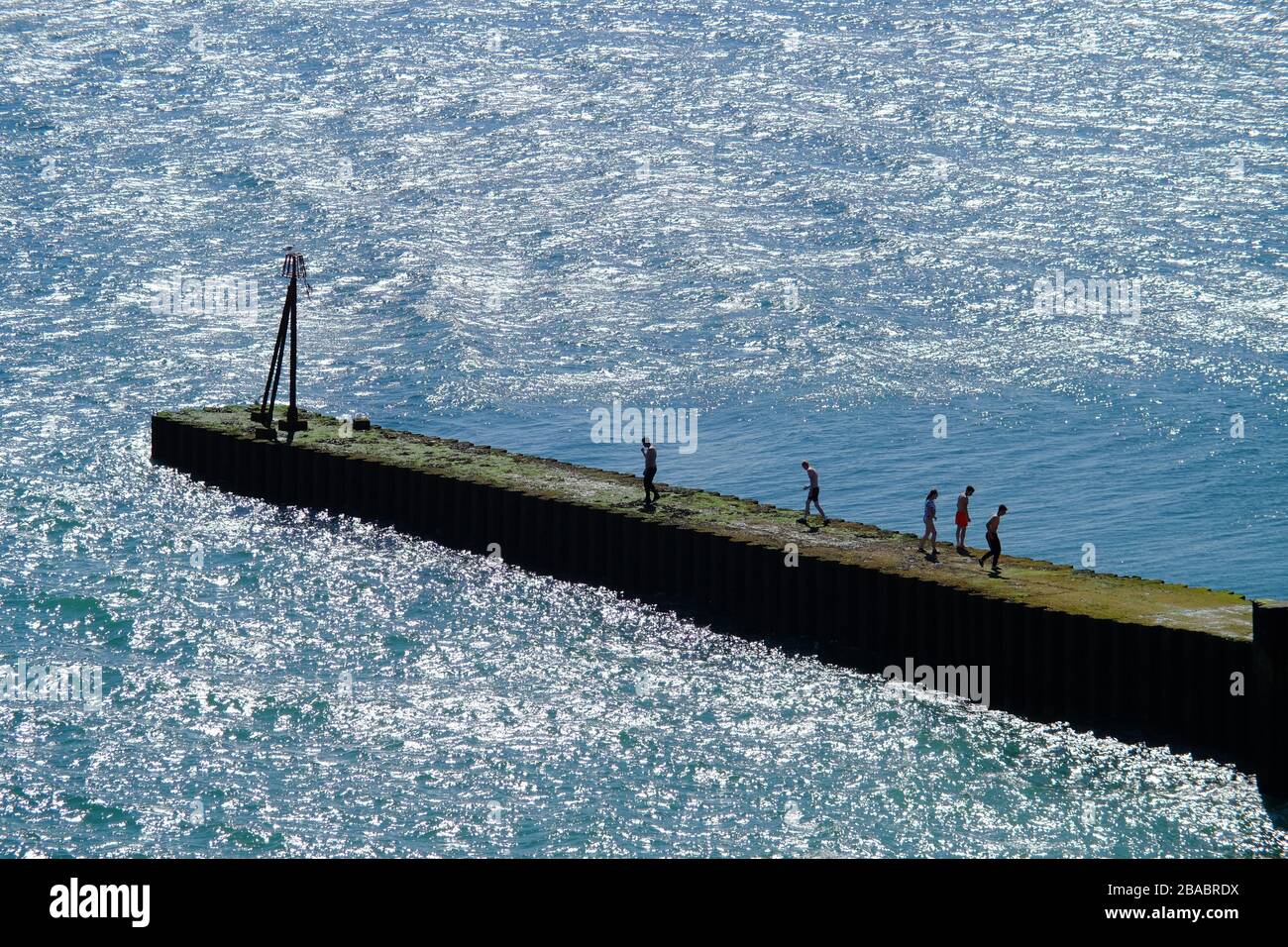Teens playing on a breakwater during summer. Seaford, East Sussex, UK Stock Photo