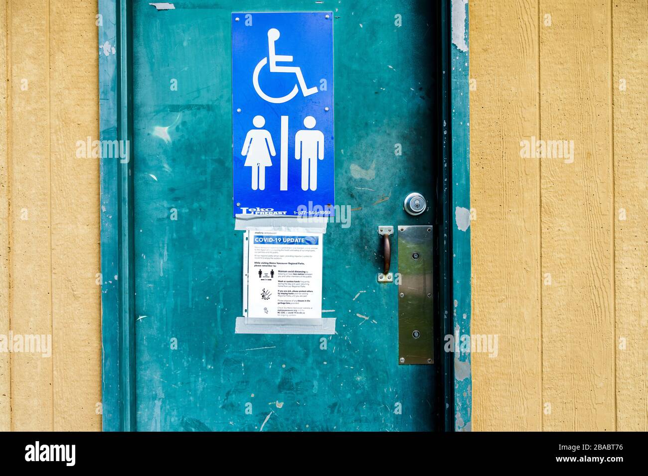 Surrey, Canada - March 25, 2020: Outdoor toilet at Tynehead Regional Park in Metro Vancouver with Corona Virus health information posted on door Stock Photo