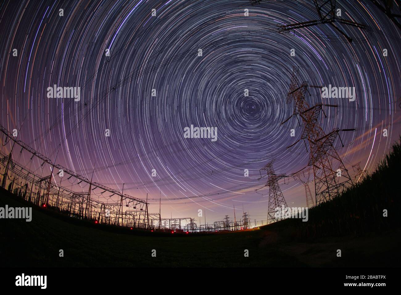 The high-voltage tower and the star track at night Stock Photo