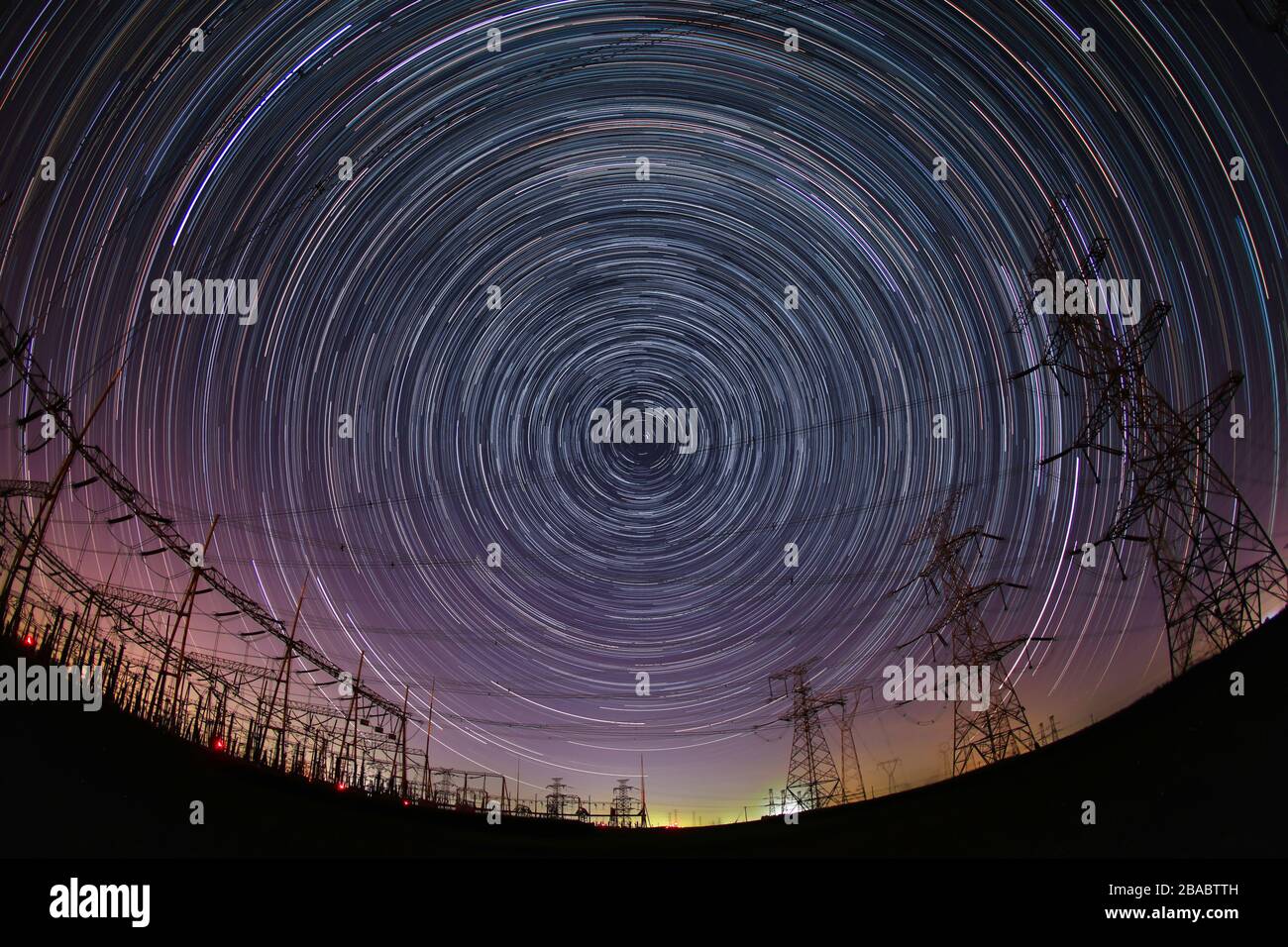 The high-voltage tower and the star track at night Stock Photo