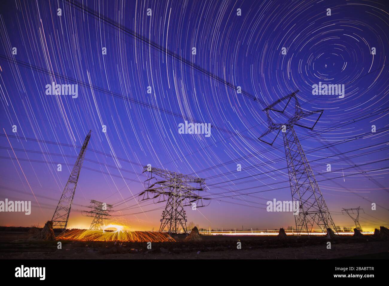 The high-voltage tower and the star track at night Stock Photo