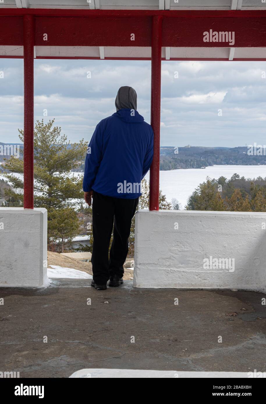 A man looking out at a frozen lake from a pavilion at Lions Lookout in ...