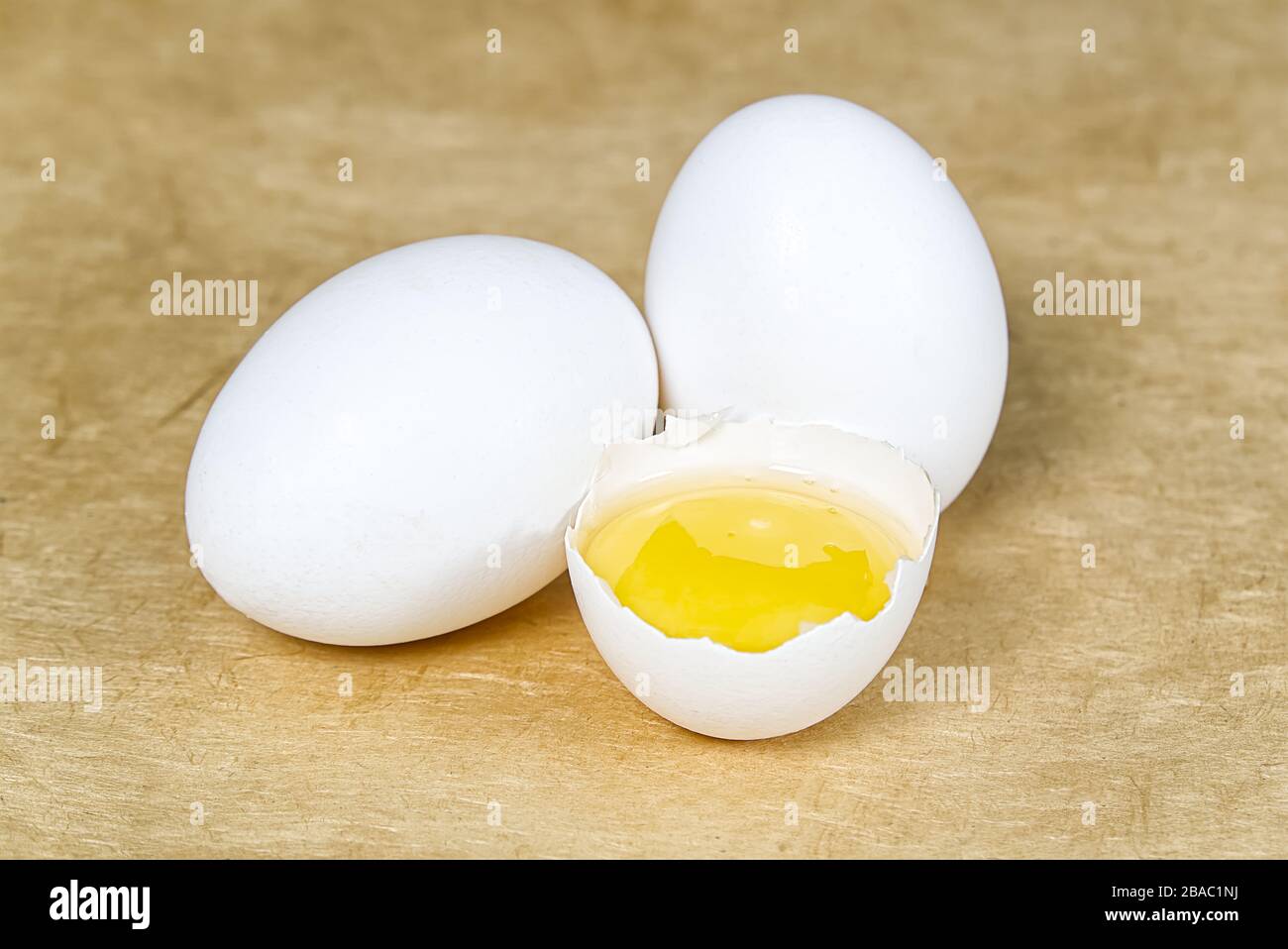 chicken white eggs with half broken egg on beige textured background Stock Photo