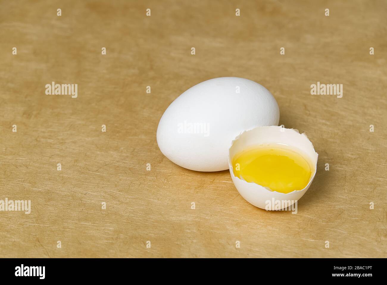 chicken white eggs with half broken egg on beige textured background Stock Photo