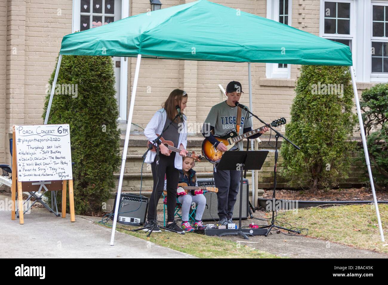 Grosse Pointe Park, Michigan, USA. 26th Mar, 2020. Nolan Eszes, 14, and his sisters Hadley, 11, and Sidney, 6, play a porch concert for their neighbors. They have played a concert every evening since Michigan Governor Gretchen Whitmer ordered residents to 'shelter in place' because of the coronavirus pandemic. Credit: Jim West/Alamy Live News Stock Photo