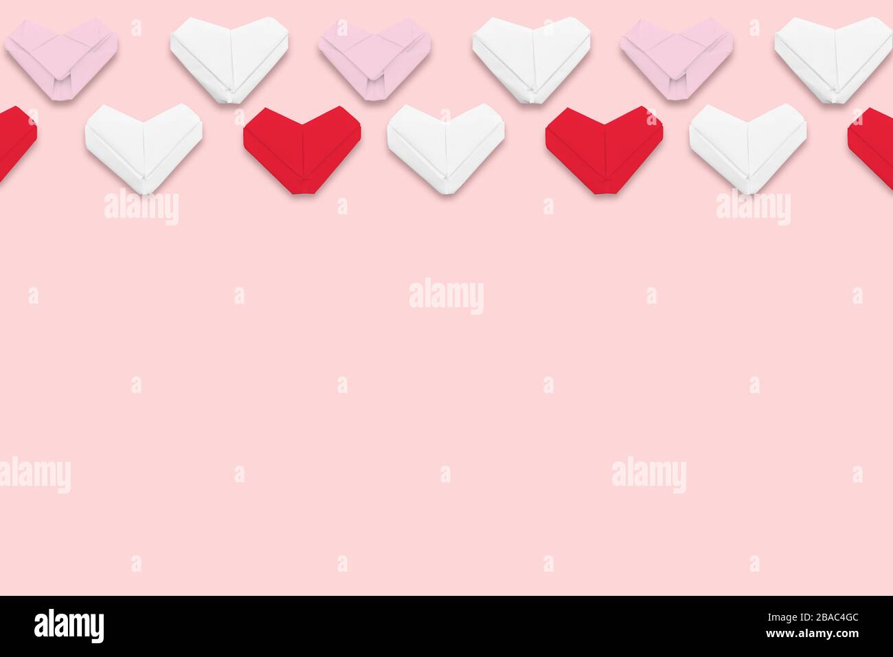 Flat lay red and white paper origami hearts on pink background ...