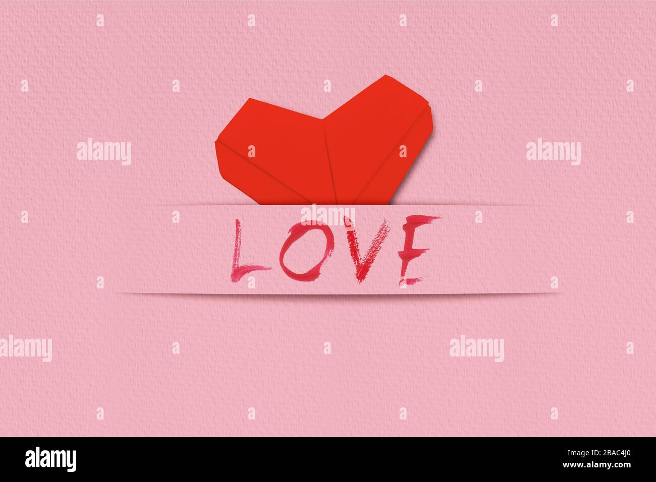 Red origami hearts with word love on pink paper background. Handcrafted ...