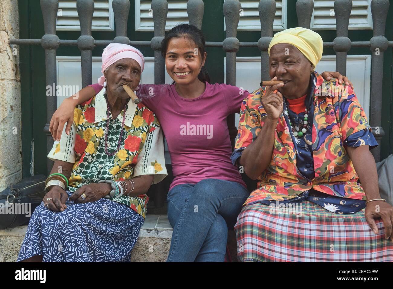 Cigar smoking women and a tourist, Havana, Cuba Stock Photo