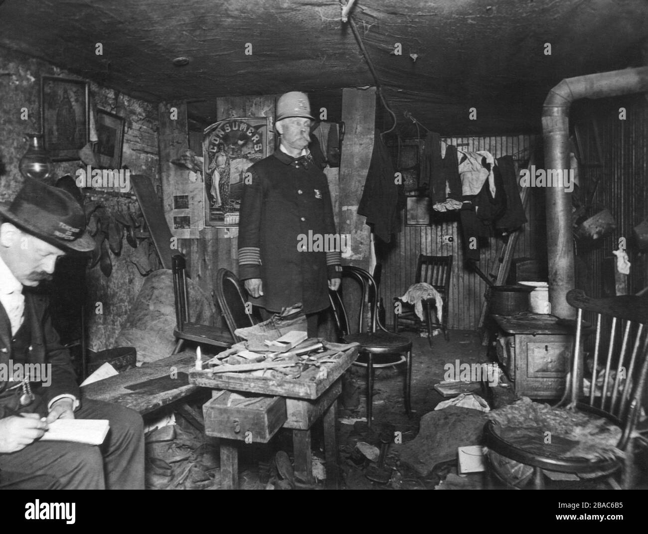 New York City policeman and a housing inspector in a cluttered basement ...