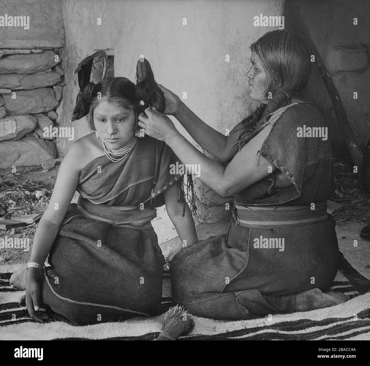 A Hopi woman dresses the hair of young unmarried women, ca. 1900, by
