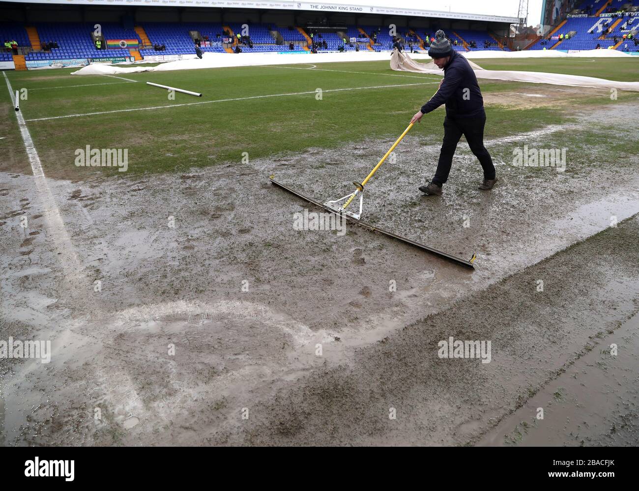 Ground staff members push water off the pitch ahead of the match Stock Photo