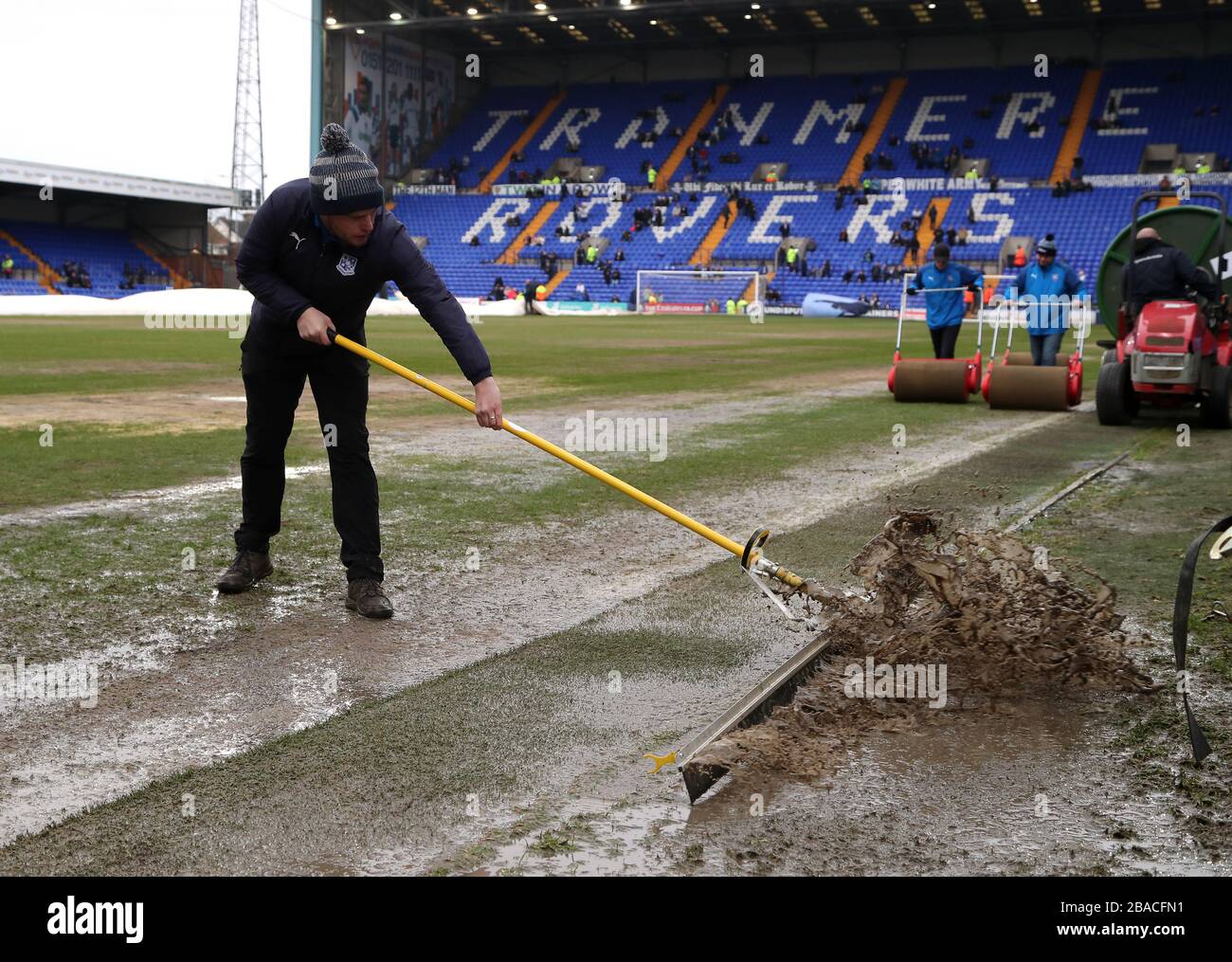Ground staff members push water off the pitch ahead of the match Stock Photo