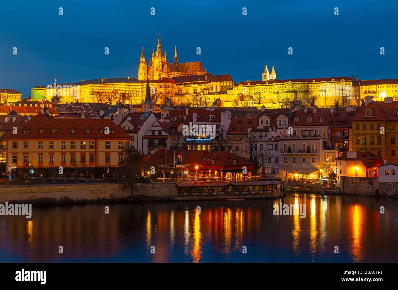 Prague Castle, also known as Hradcany Castle, at night along the Vltava river and the Saint Vitus cathedral on top, Czech Republic. Stock Photo