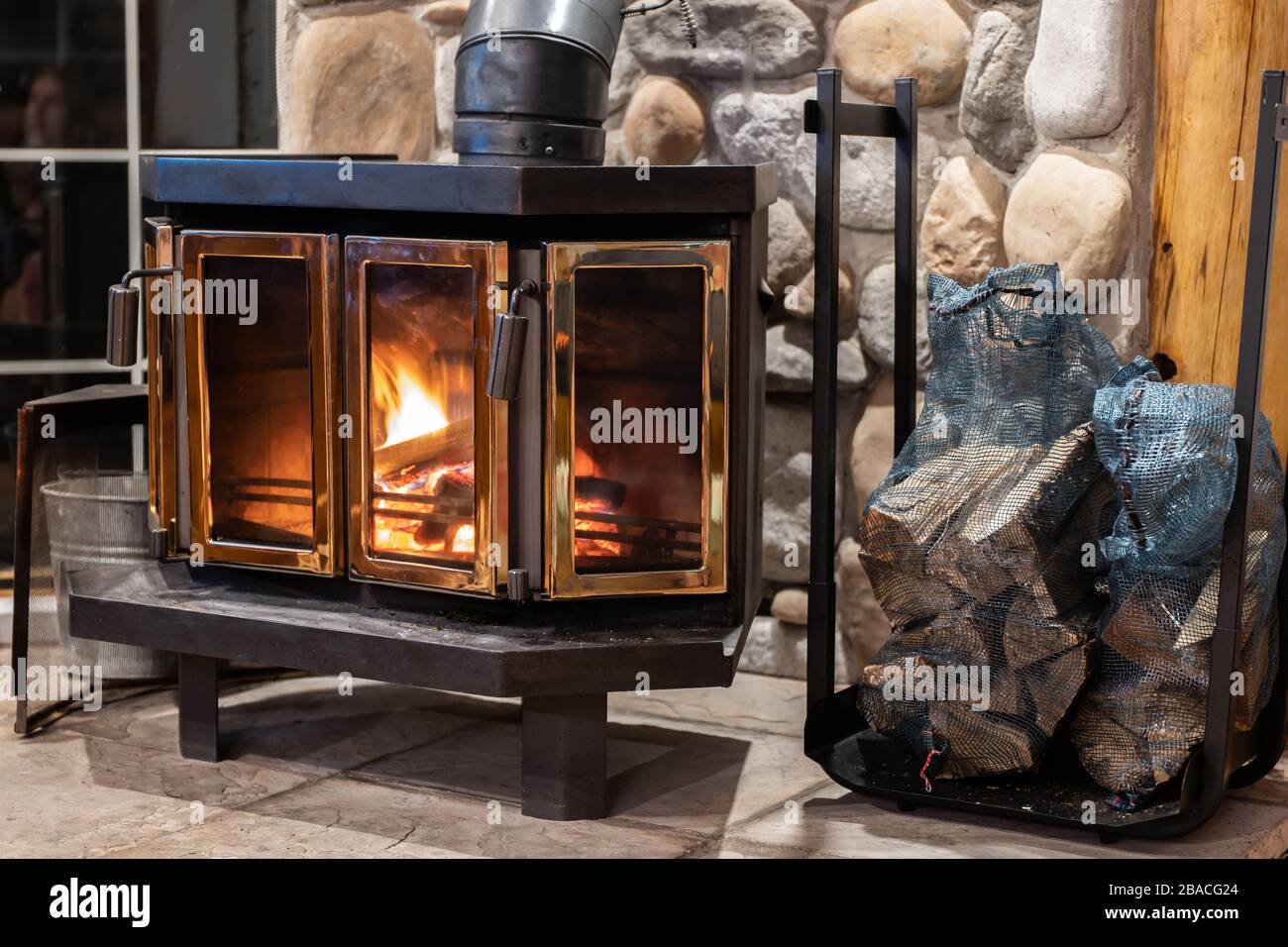 Wood stove fireplace with metal body and glass door in house with cozy  interior Stock Photo - Alamy