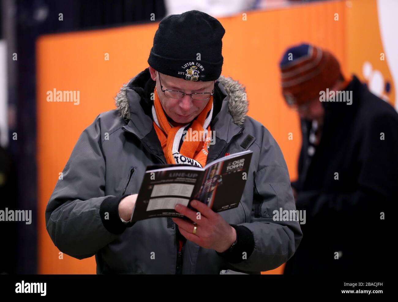 Luton Town fan reads the match day programme ahead of the match Stock Photo