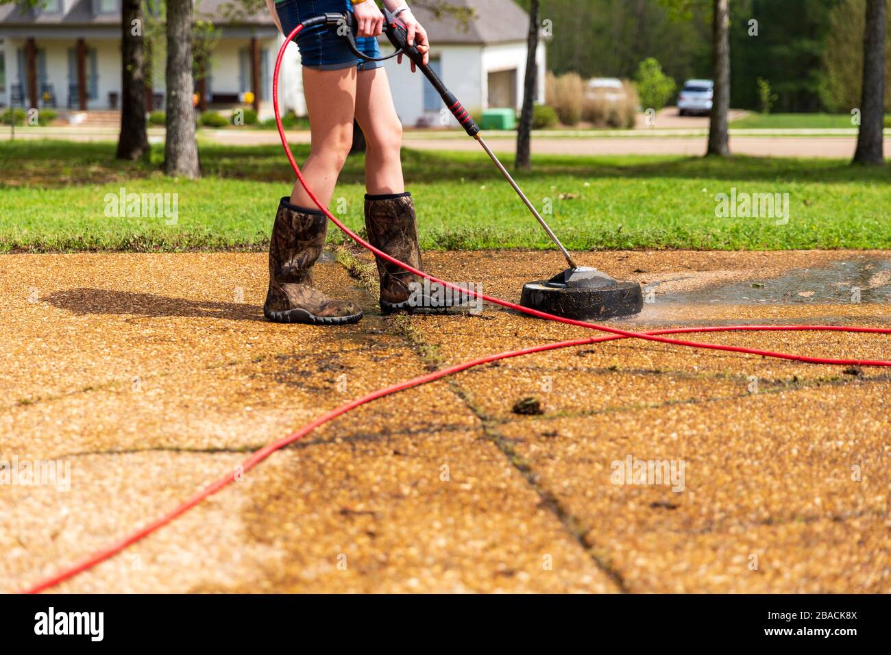 Woman pressure washing to clean driveway of a home Stock Photo Alamy