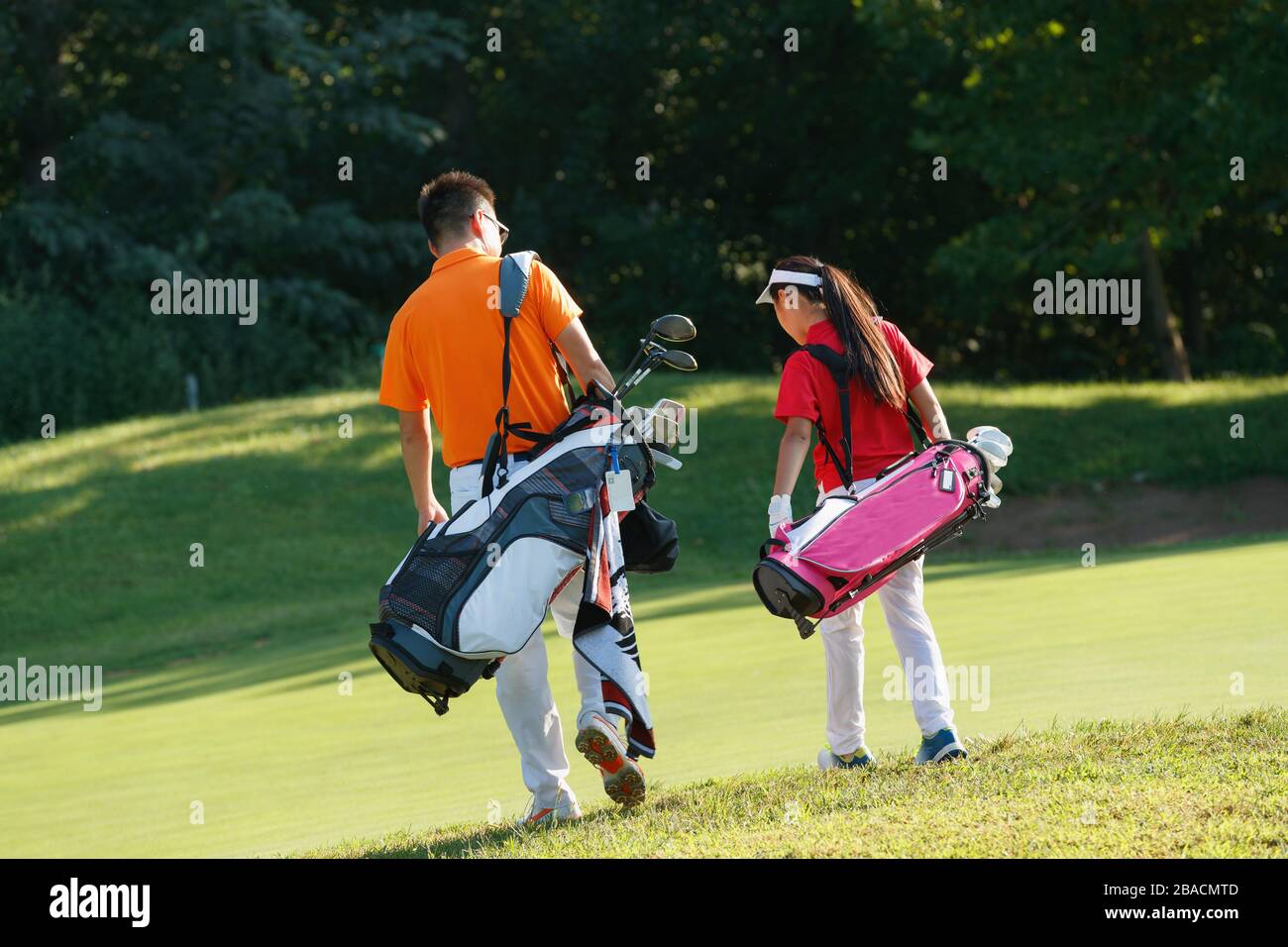 The coach on the pitch and students carrying golf bag back on foot