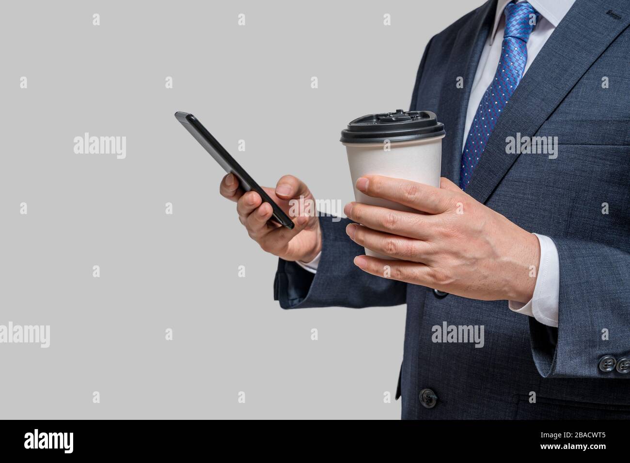 A businessman holding a white paper cup and a smartphone. With copy space. Stock Photo