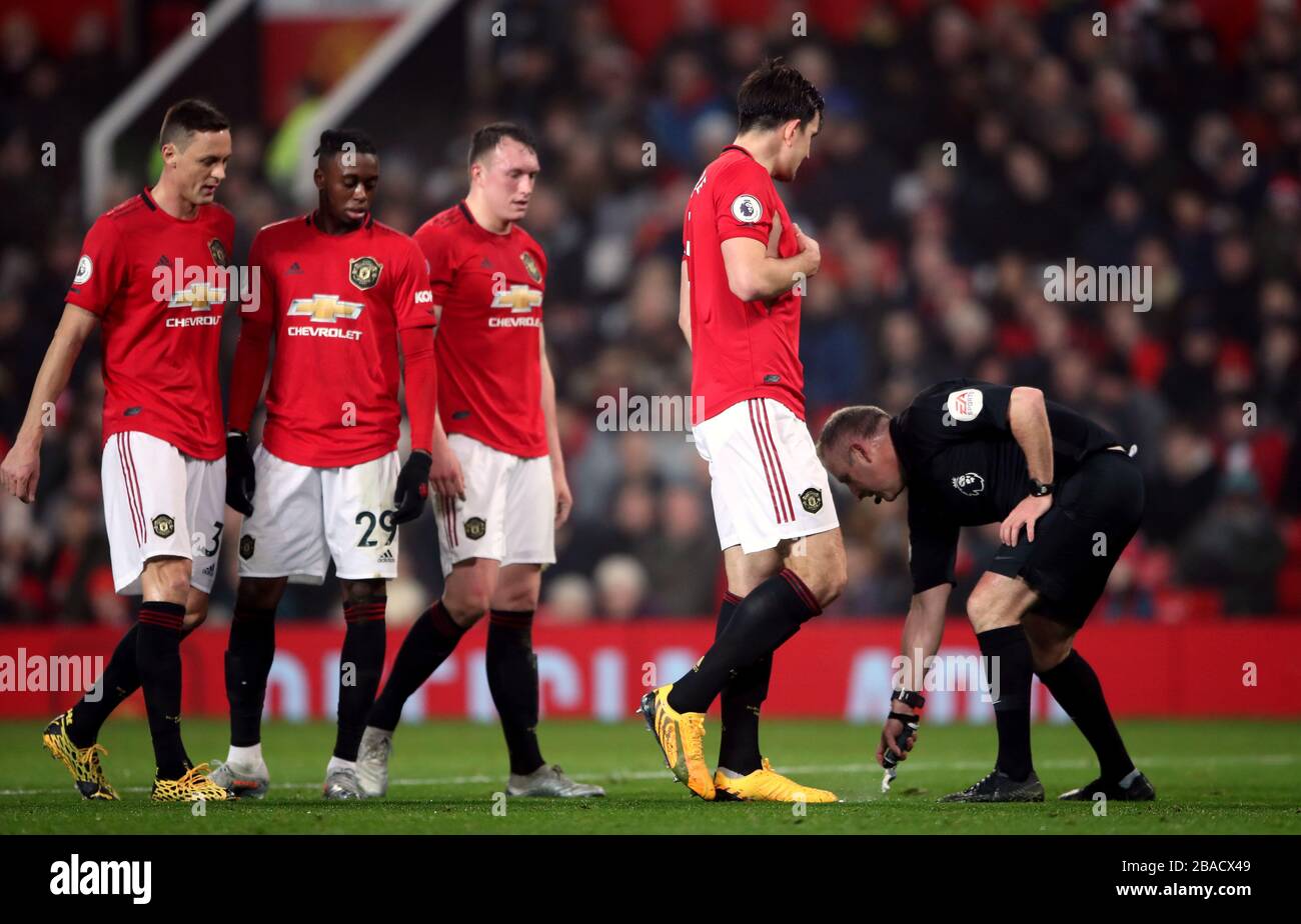 Manchester United's (left-right) Nemanja Matic, Aaron Wan-Bissaka, Phil Jones and Harry Maguire look on as referee Jonathan Moss sprays the foam line to identity the ten yards distance required for a free kick Stock Photo