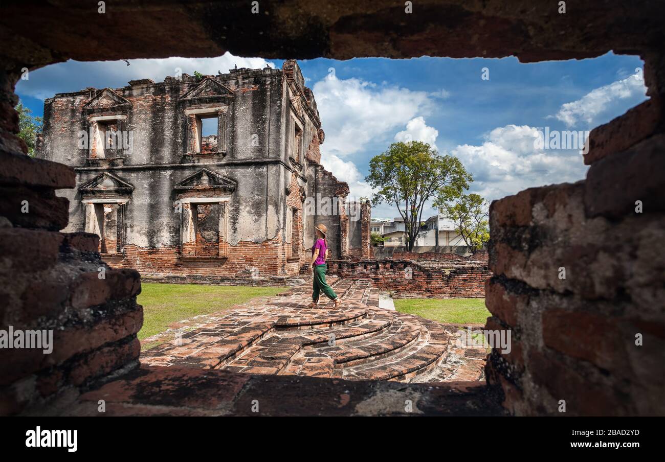 Woman tourist in hat walking at ancient ruined Temple of city Lopburi, Thailand Stock Photo