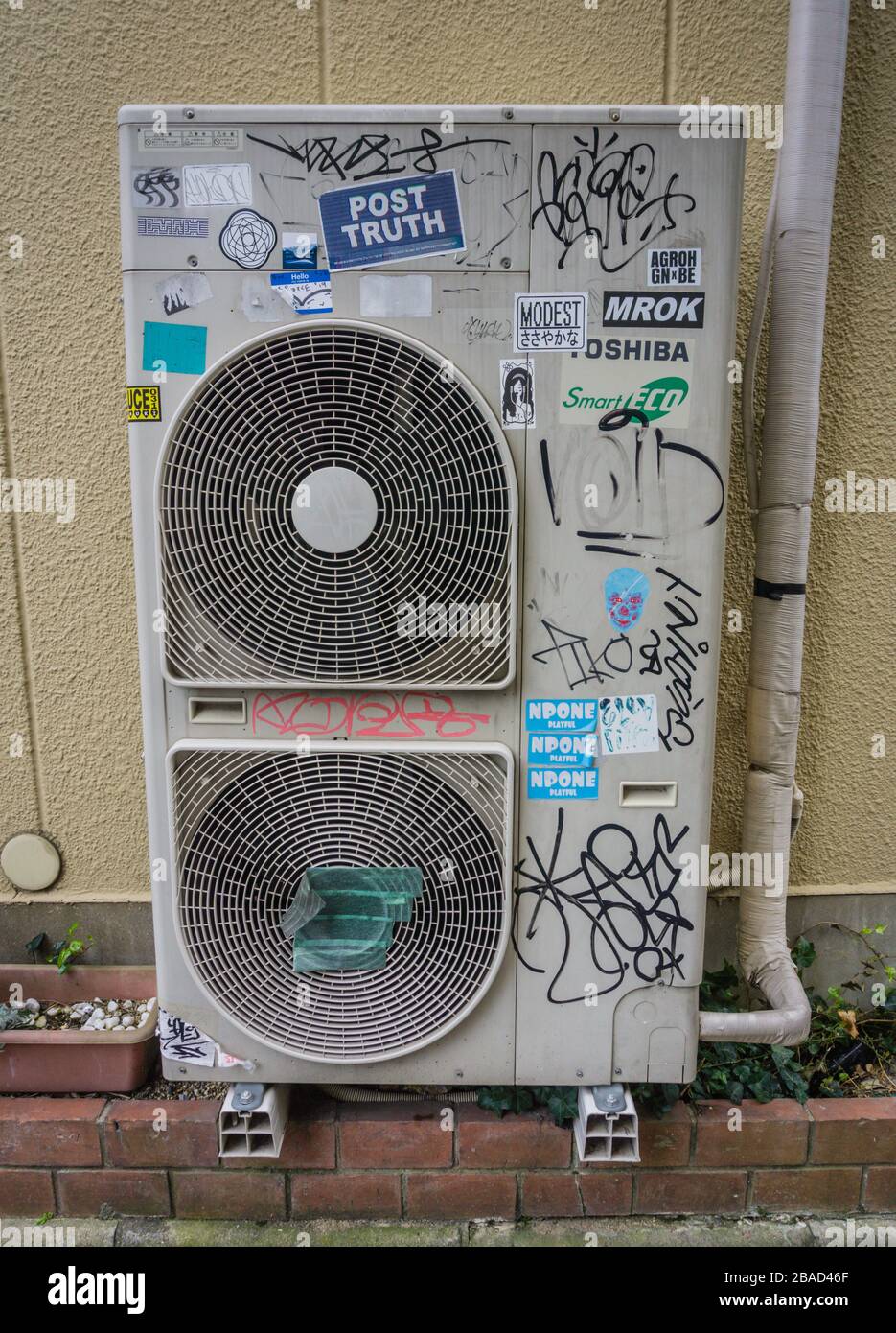 Old air conditioning unit covered in graffiti and stickers outside a house in Nara Japan Stock Photo