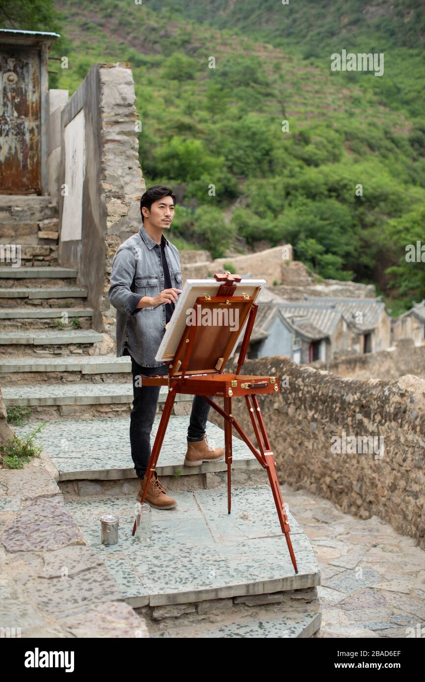 Young Chinese artist painting outdoors Stock Photo