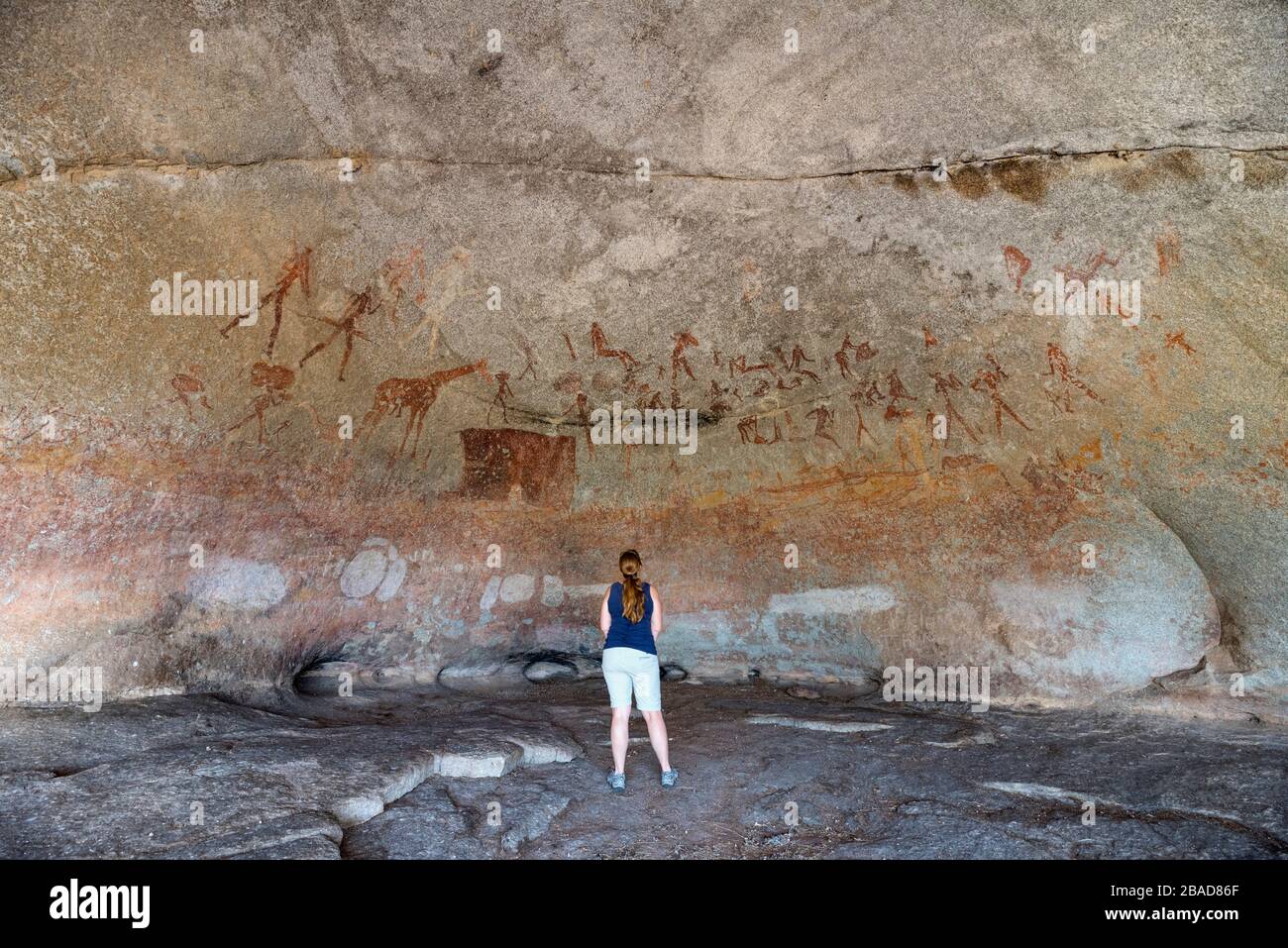 A tourist admires the San rock art in Silozwane cave, Matobo National Park, Zimbabwe. Stock Photo