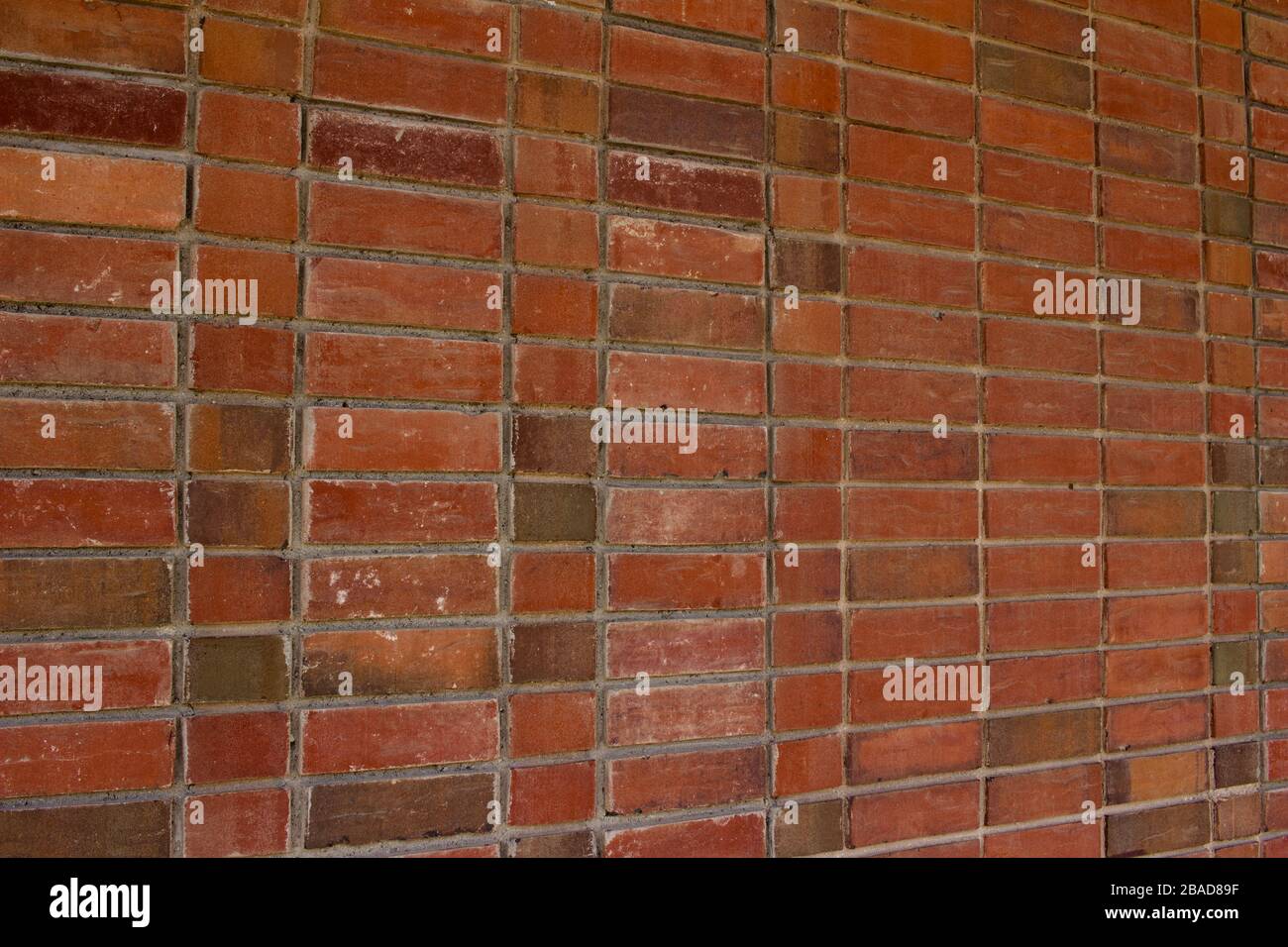 Older weathered red and brown brick wall texture background with a unique stack bond brickwork pattern. Stock Photo