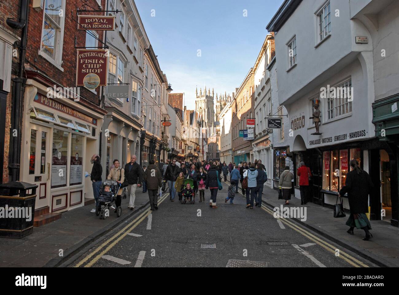 Shoppers and visitors in busy Low Petergate leading into Shambles in the old historical quarter of the city of York in Yorkshire, Britain.   A street Stock Photo