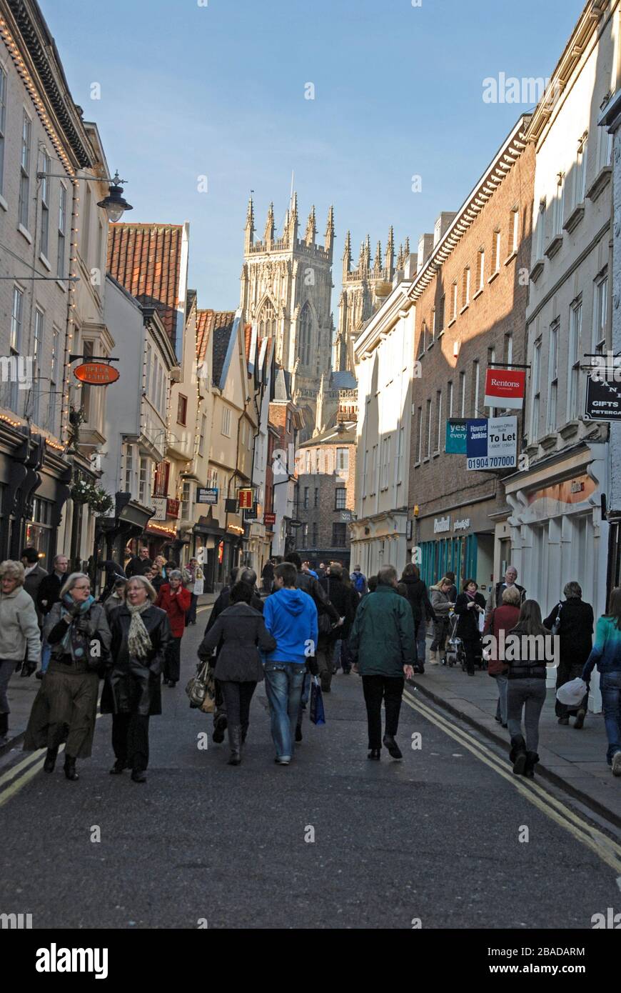 Shoppers and visitors in busy Low Petergate leading into Shambles in the old historical quarter of the city of York in Yorkshire, Britain.   A street Stock Photo