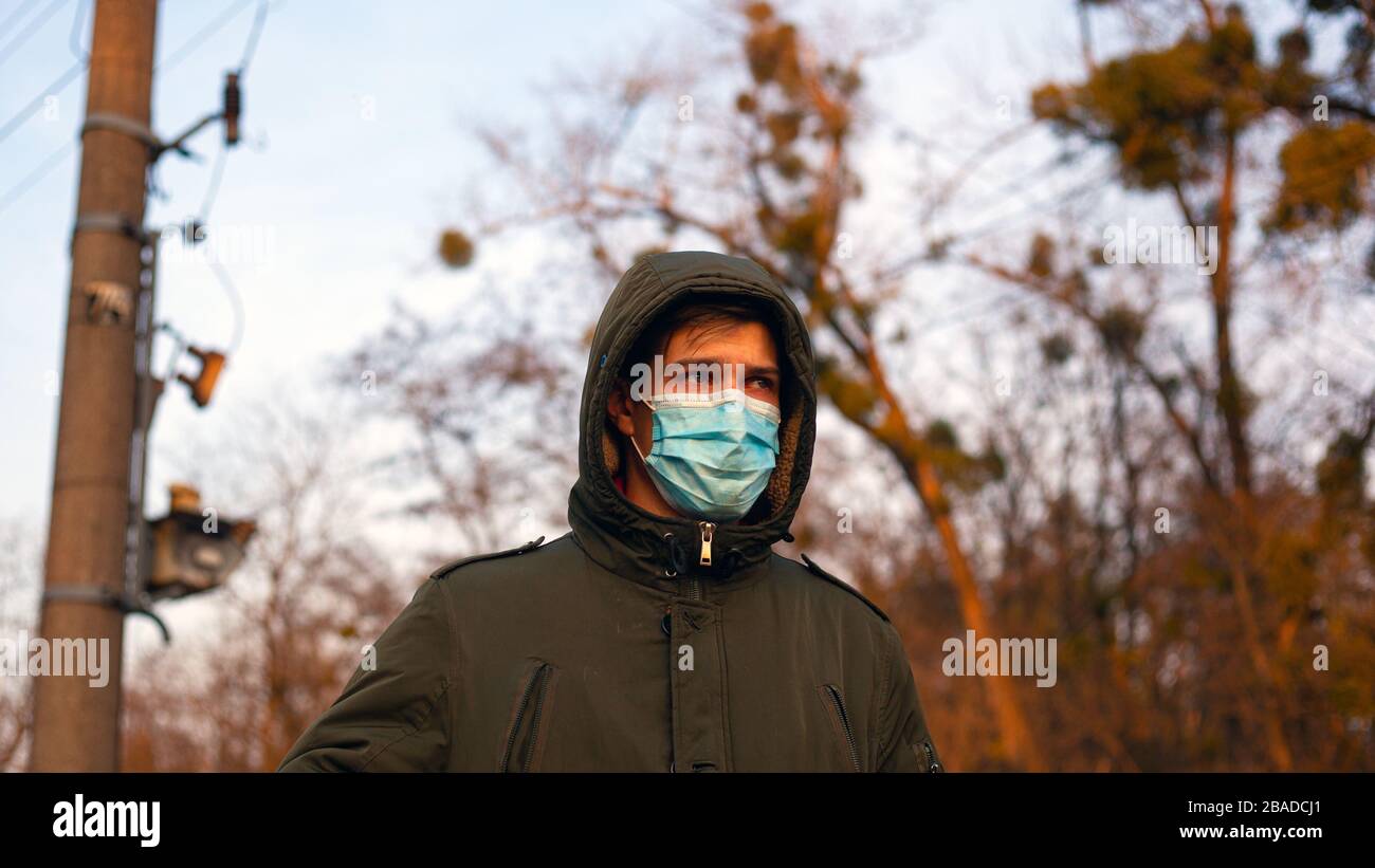 young man in medical protective mask stands on the street. quarantine isolation pandemic 2019-nCoV. coronavirus flu outbreak. Stock Photo