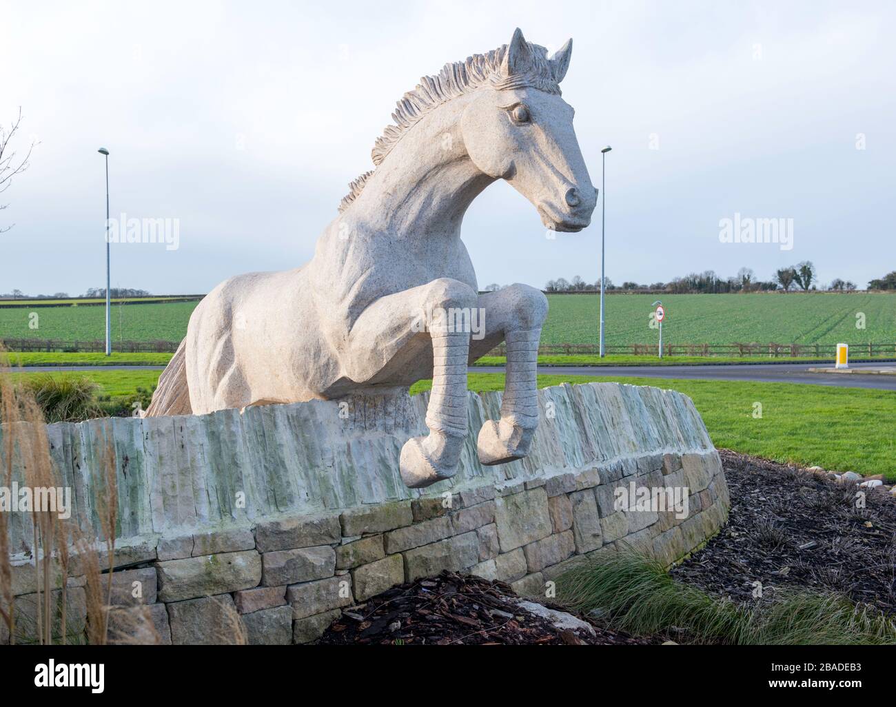 Sculpture, in the middle of a roundabout in Wetherby, West Yorkshire, of a racehorse jumping over an obstacle Stock Photo