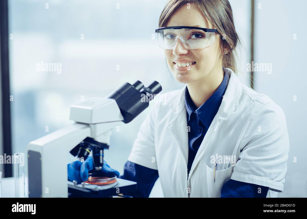 Young scientist looking through a microscope in a laboratory. Young scientist doing some research. Stock Photo