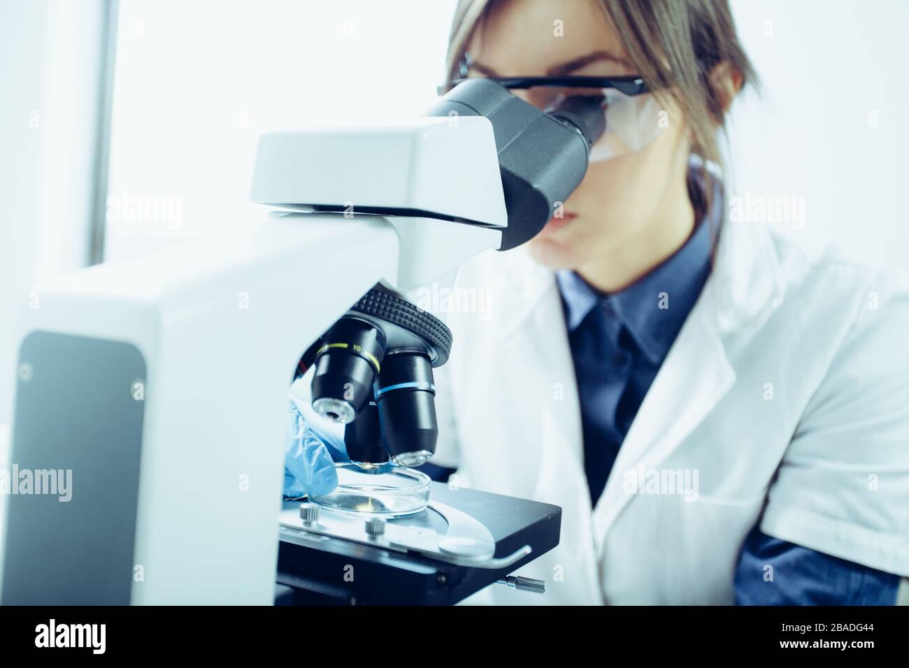 Young scientist looking through a microscope in a laboratory. Young scientist doing some research. Stock Photo