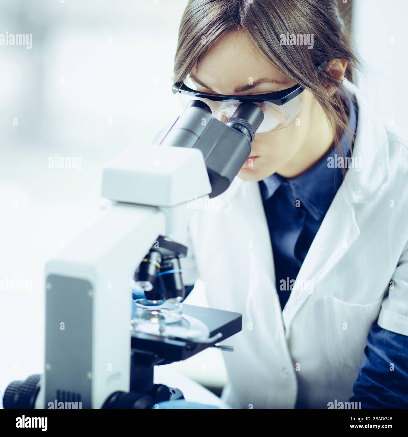 Young scientist looking through a microscope in a laboratory. Young scientist doing some research. Stock Photo