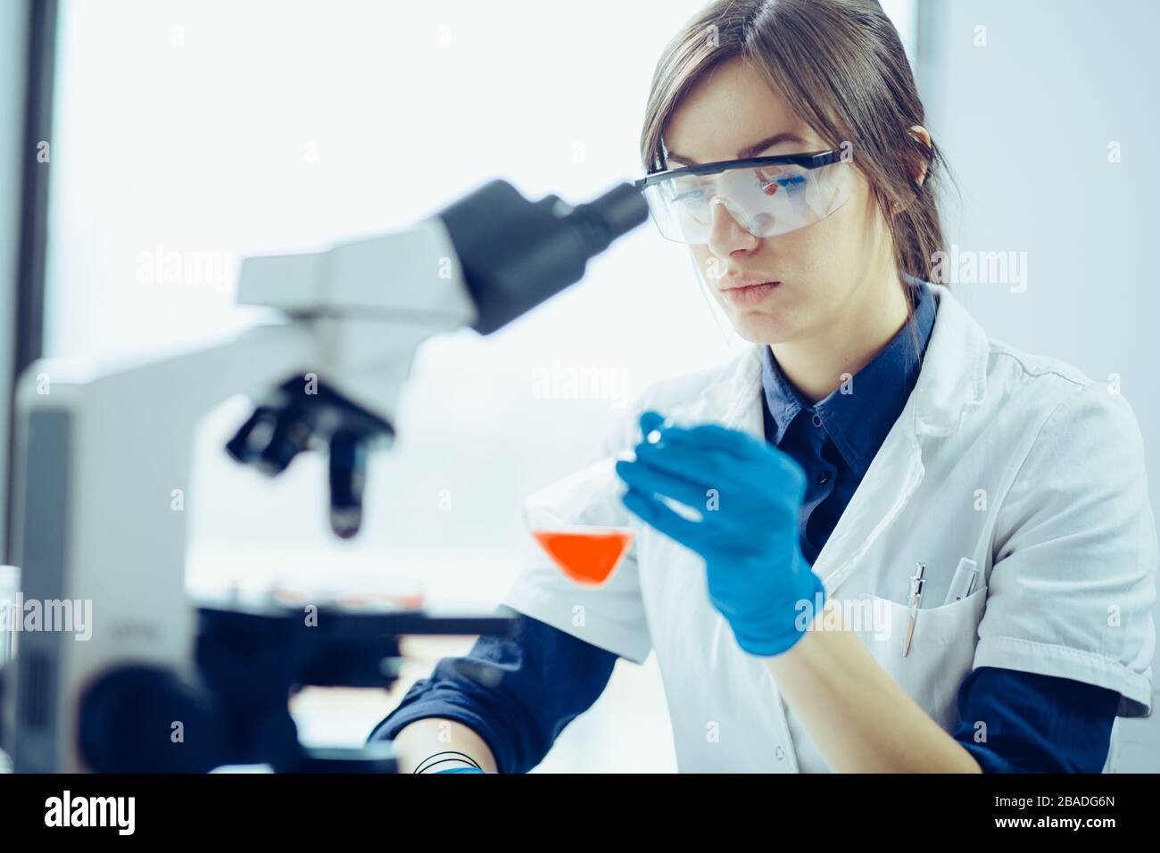 Young scientist looking through a microscope in a laboratory. Young scientist doing some research. Stock Photo