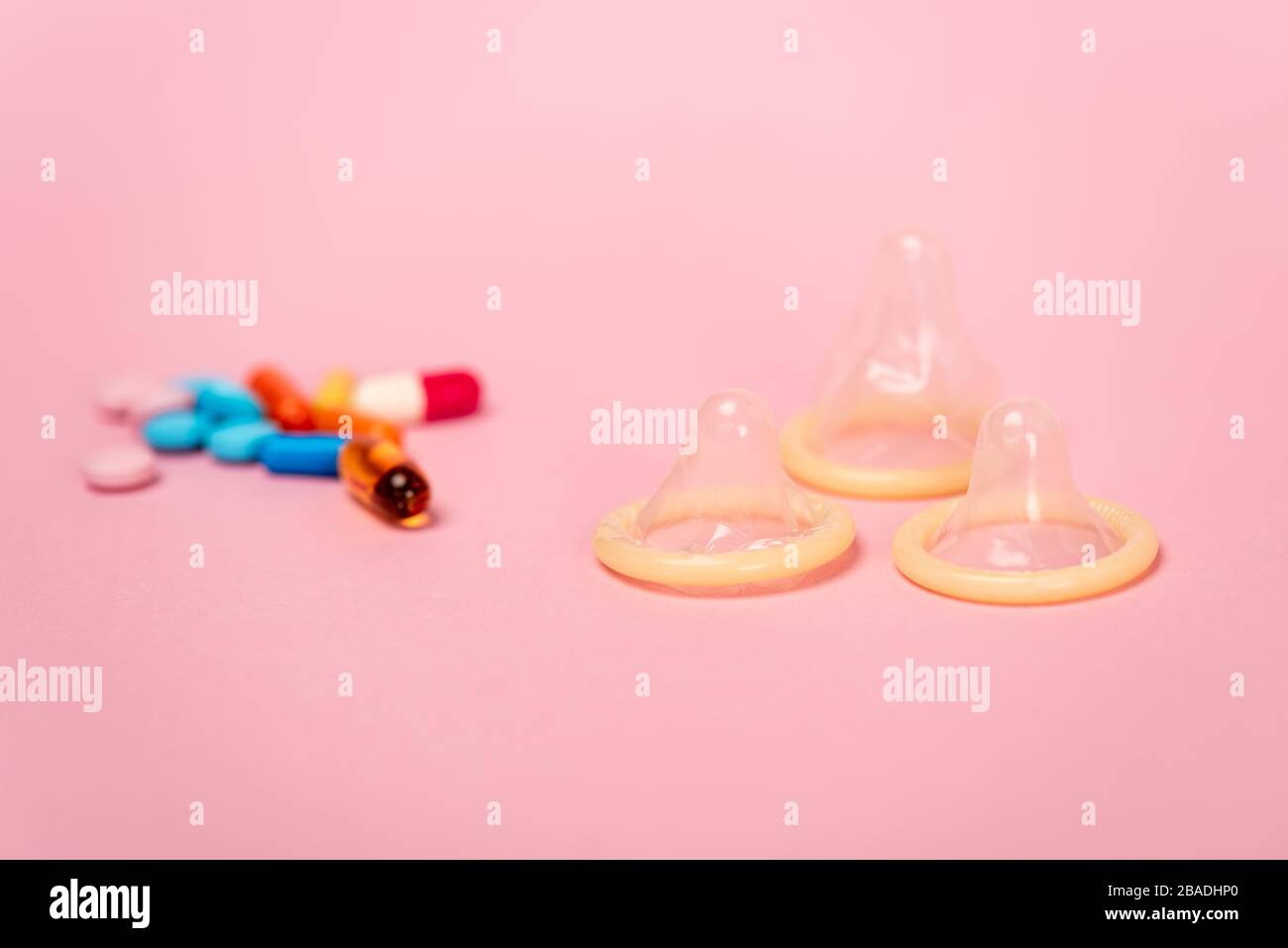 Selective focus of condoms and birth control pills on pink background Stock Photo