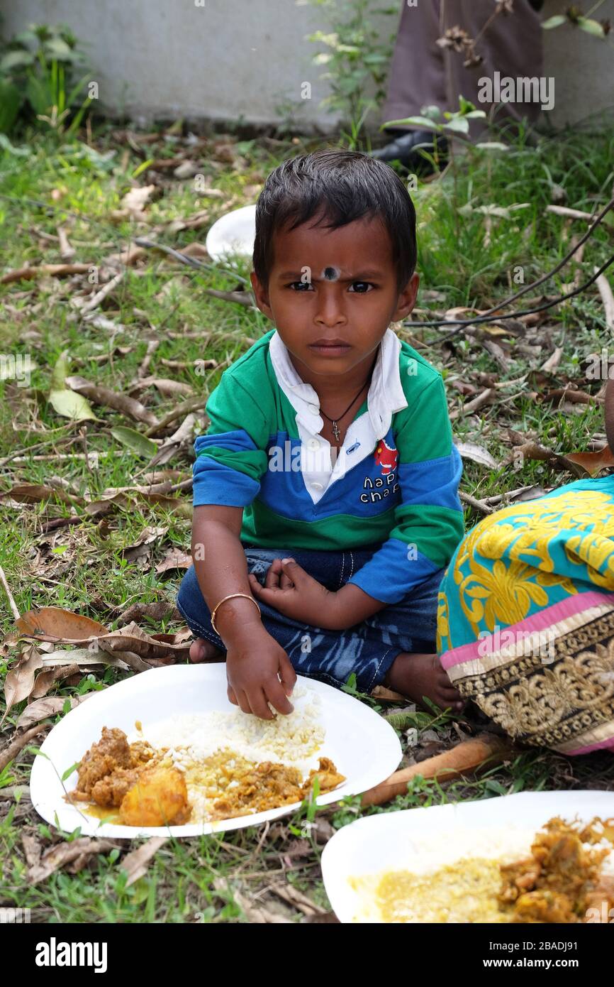 A young boy eats lunch sitting on the ground in Kumrokhali village, West Bengal, India Stock Photo