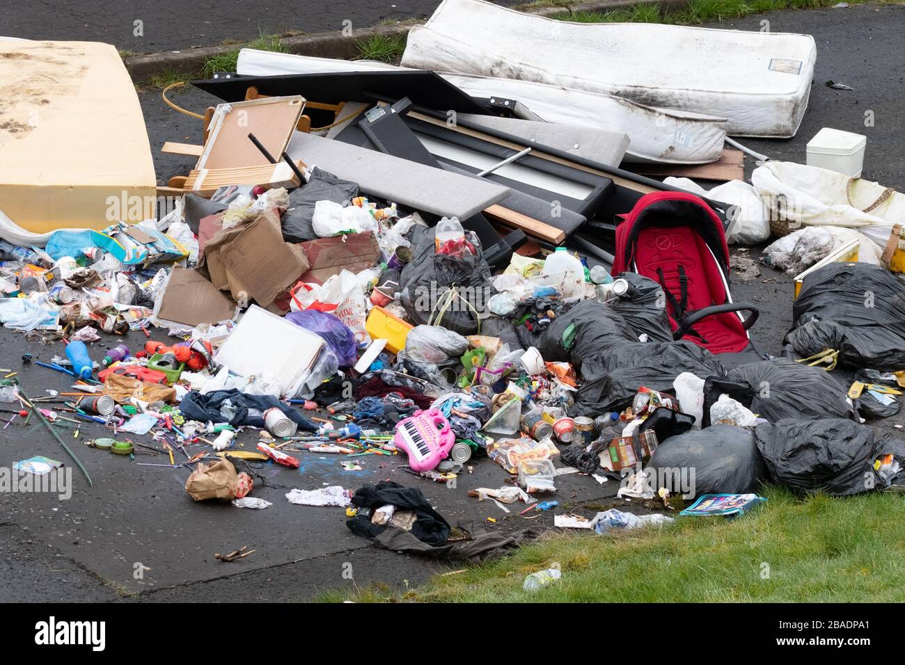 fly tipping uk - large pile of household rubbish including childrens toys and mattresses - Easterhouse, Glasgow, Scotland, UK Stock Photo